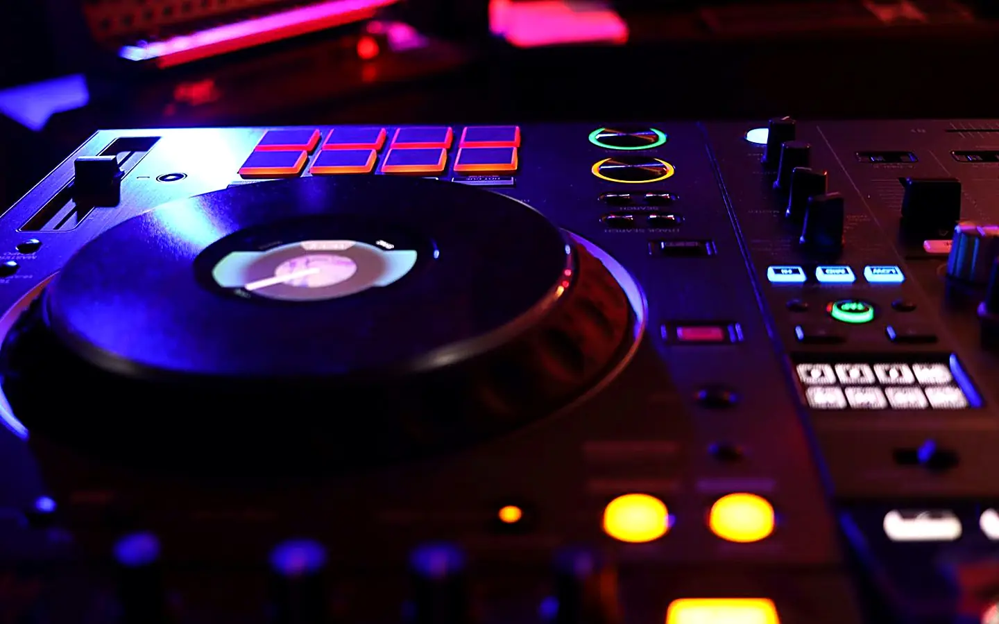 Professional DJ controller under colorful event lighting